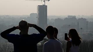 Des athlètes font une pause alors qu'ils courent sur la colline de San Siro et regardent l'horizon de Milan, Italie, mardi 20 février 2024.