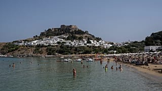 Tourists enjoy the beach and the sea in Lindos, on the Aegean Sea island of Rhodes, southeastern Greece, on July 27, 2023.