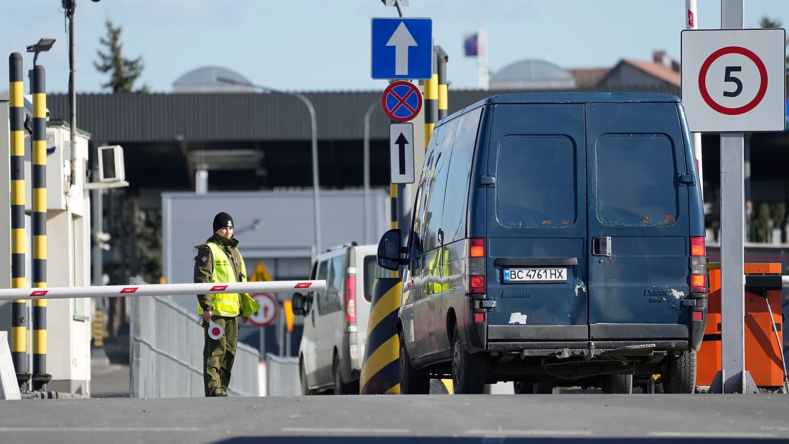 Un guardia fronterizo polaco da instrucciones mientras los conductores esperan cruzar la frontera de Polonia a Ucrania en Medyka, Polonia, el sábado 19 de febrero de 2022.