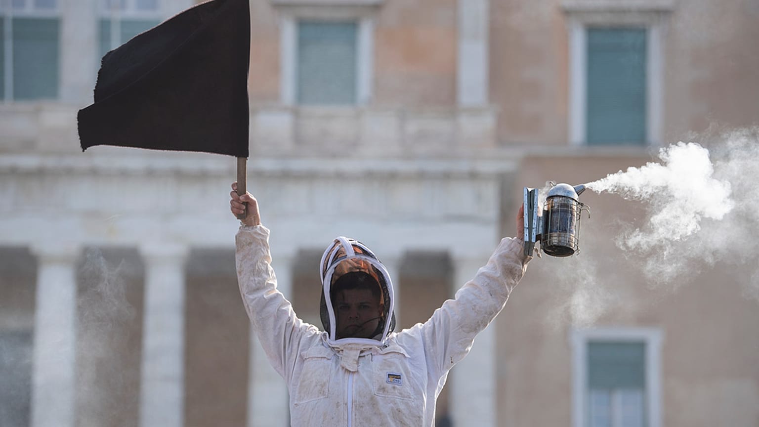 Ein Imker hält während einer Demonstration vor dem griechischen Parlament in der Innenstadt von Athen, Griechenland, am Donnerstag, dem 22. Februar 2024, eine schwarze Flagge.