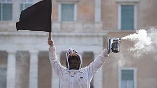 Ein Imker hält während einer Demonstration vor dem griechischen Parlament in der Innenstadt von Athen, Griechenland, am Donnerstag, dem 22. Februar 2024, eine schwarze Flagge.