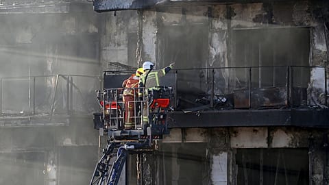 Firefighters work at a burnt out residential building in Valencia, Spain, Friday, Feb. 23, 2024.