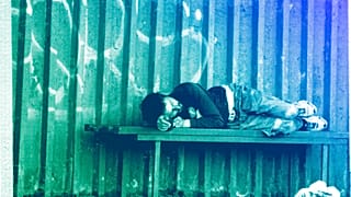 A homeless man sleeps on a bench at a bus stop on the outskirts of Kyiv, June 2022
