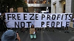 Demonstrators hold up placards as they protest outside the British energy regulator, Ofgem. London, Friday, Aug. 26, 2022. 