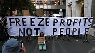 Demonstrators hold up placards as they protest outside the British energy regulator, Ofgem. London, Friday, Aug. 26, 2022.