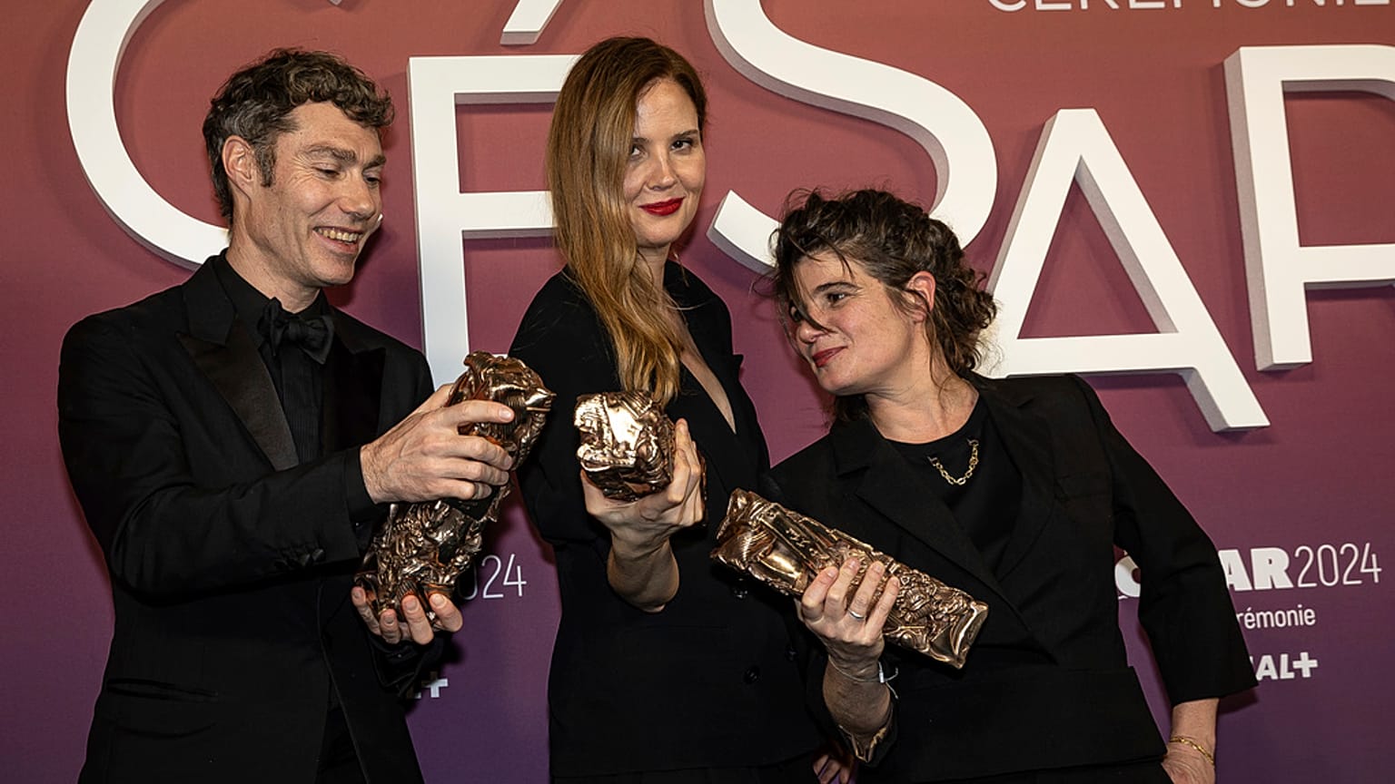 Justine Triet sacrée meilleure réalisatrice (au centre), aux côtés des producteurs du film Anatomie d'une chute, Marie-Ange Luciani et David Thion.