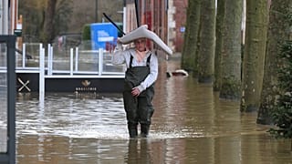 A woman carries a chair on her head as she walks in a flooded street of Arques, northern France in January as heavy rains pummeled the Pas-de-Calais and Nord regions 