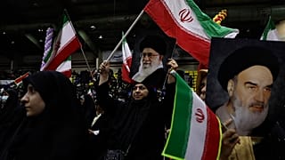 Mujeres iraníes ondean banderas de su país con carteles del líder supremo, el ayatolá Ali Jamenei, y del difunto fundador revolucionario, el ayatolá Jomeini