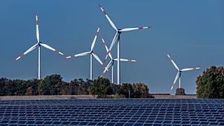 Turbine eoliche girano dietro un parco solare a Rapshagen, in Germania.