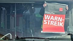 An employee of Hallesche Verkehrs-AG (HAVAG) attaches a strike poster in the window of a bus, at a depot, in Halle, Germany, Thursday, Feb. 29, 2024.