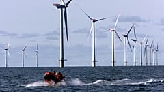 Ein Schnellboot fährt auf der Nordsee, 14 Kilometer westlich des kleinen Dorfes Blavand bei Esbjerg, Dänemark, an Turbinen vorbei.