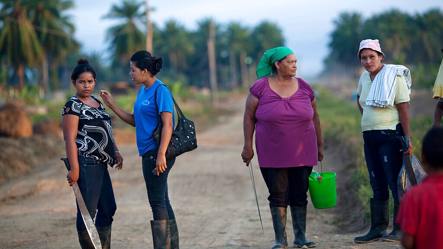 In this May 7, 2012 photo, women, with machetes in hand, wait for a truck to drive them to their work areas of their African palm tree plantation in La Confianza, Honduras.