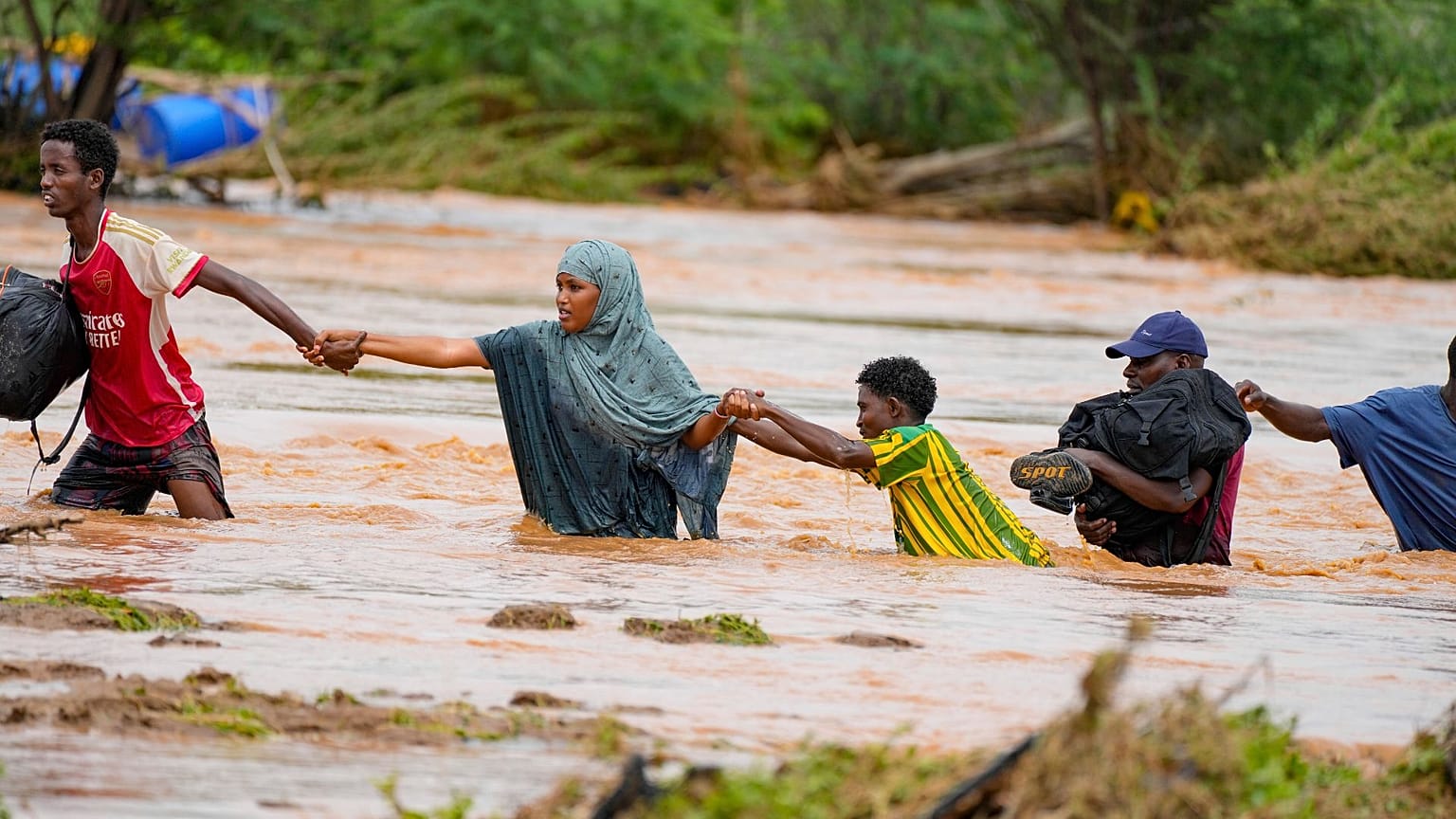 Moradores atravessam uma estrada danificada pelas chuvas do El Niño em Tula, no condado de Tana River, no Quénia, em 25 de novembro de 2023. 