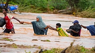 Moradores atravessam uma estrada danificada pelas chuvas do El Niño em Tula, no condado de Tana River, no Quénia, em 25 de novembro de 2023.