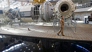 Moskova yakınlarındaki Rus Kozmonotlar Eğitim Merkezi'nde yer alan Uluslararası Uzay İstasyonu maketinin önünden geçen bir Rus mühendis (arşiv)