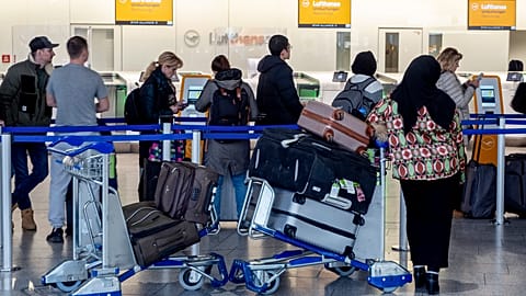 Menschen stehen am Donnerstag, den 7. März 2024, in einem Terminal des Frankfurter Flughafens für Informationen an.