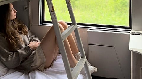 Sarah Marks, of London, looks out at the Italian countryside on TrenItalia's Intercity Notte sleeper train from Palermo to Rome, 10 June 2023.