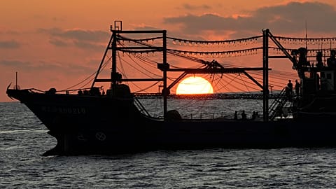 The sun rises while a suspected Chinese militia ship blocks Philippine coast guard ship, not shown, in the disputed South China Sea Tuesday, March 5, 2024.