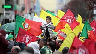 Uma criança segura uma flor e uma bandeira do Partido Socialista é erguida por cima da multidão durante uma ação de campanha eleitoral com o líder do Partido Socialista, 2024