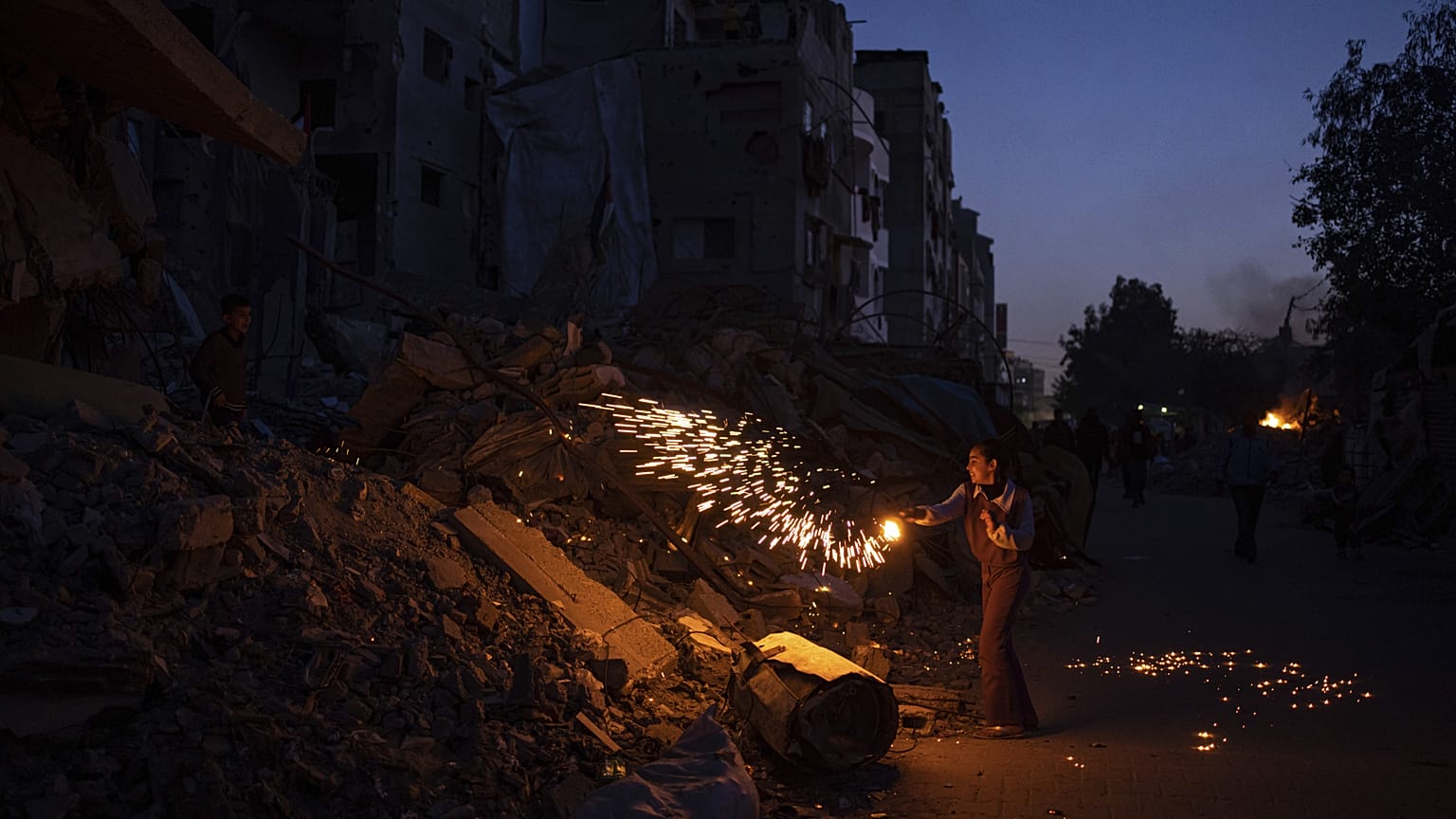 طفل فلسطيني يلعب بالألعاب النارية وهو يحتفل ببداية شهر رمضان بجوار مبنى سكني مدمر في غزة
