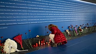 Una mujer enciende una vela en un monumento a las víctimas del atentado en el tren dentro de la estación de tren de Atocha en Madrid, España, el lunes 11 de marzo de 2024.