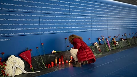 A woman lights a candle at a memorial to the victims of the train bombing inside the Atocha train station in Madrid, Spain, Monday, March 11, 2024.