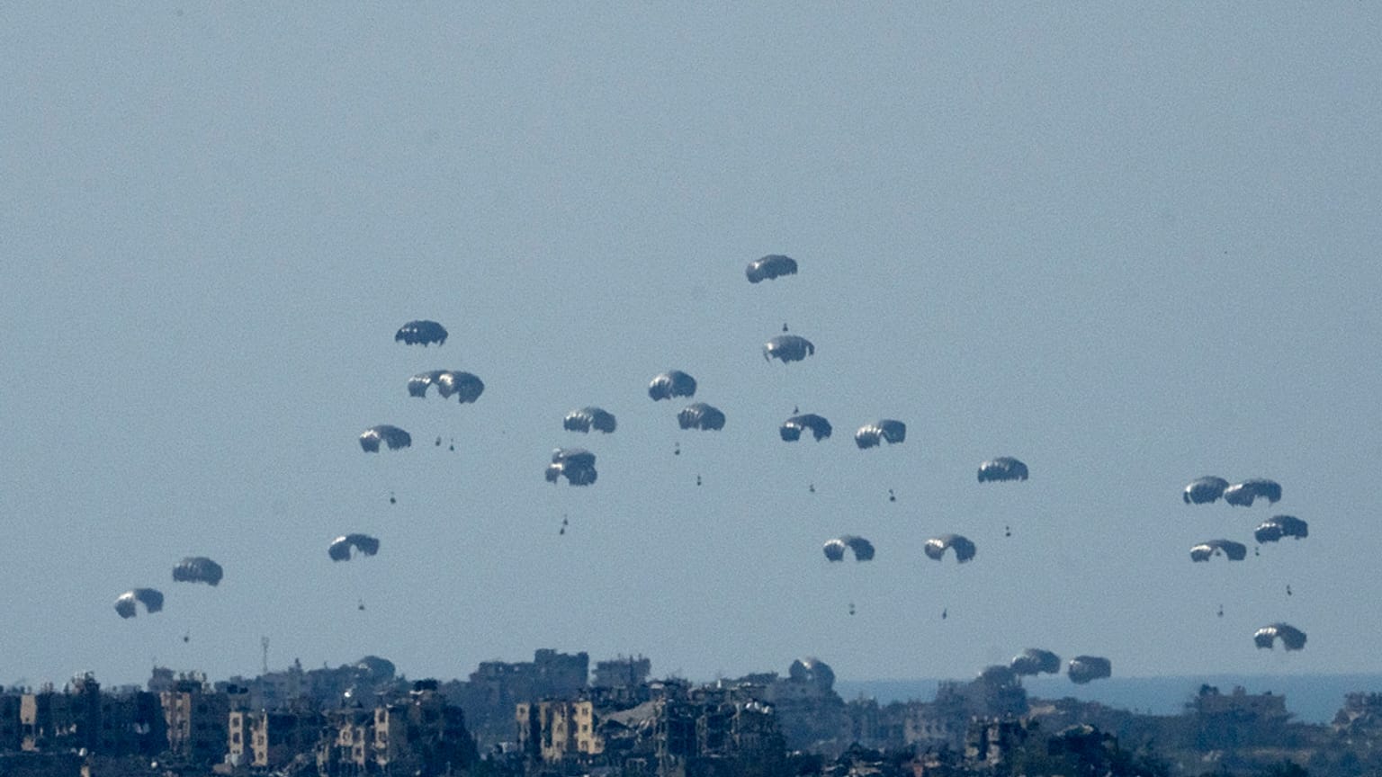 Parachutes drop humanitarian aid into the northern Gaza Strip, as seen from southern Israel, Monday, March 11, 2024. 
