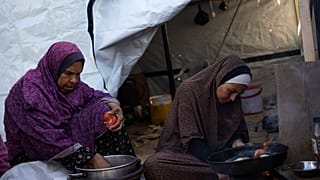 Two Palestinian women prepare food.