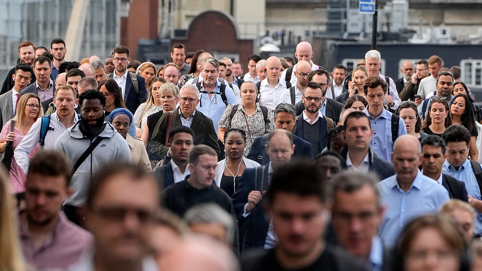 People walk over the London Bridge to work in the City of London on Monday morning, Sept. 12, 2022. 