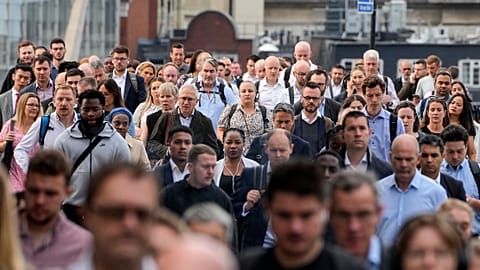 People walk over the London Bridge to work in the City of London on Monday morning, Sept. 12, 2022. 