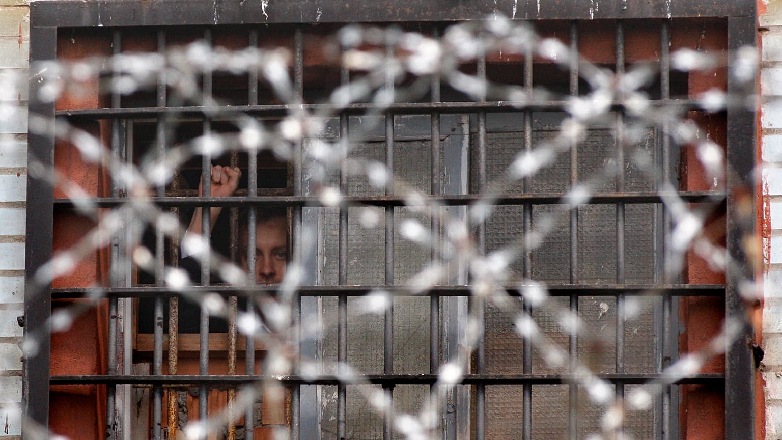 Detenido bielorruso hace gestos desde una celda de un centro de detención en Minsk, Bielorrusia, el 7 de julio de 2011.