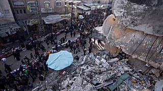 Palestinians shop at a local market next to a destroyed residential building by the Israeli airstrikes, during the Muslim holy month of Ramadan, in Rafah, Gaza Strip, Thursday