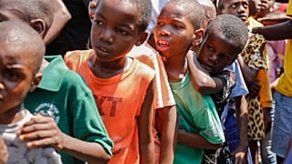 Kinder stellen sich in einer Unterkunft für von Bandengewalt vertriebene Familien in Port-au-Prince, Haiti, am Donnerstag, dem 14. März 2024, an, um Essen zu erhalten.