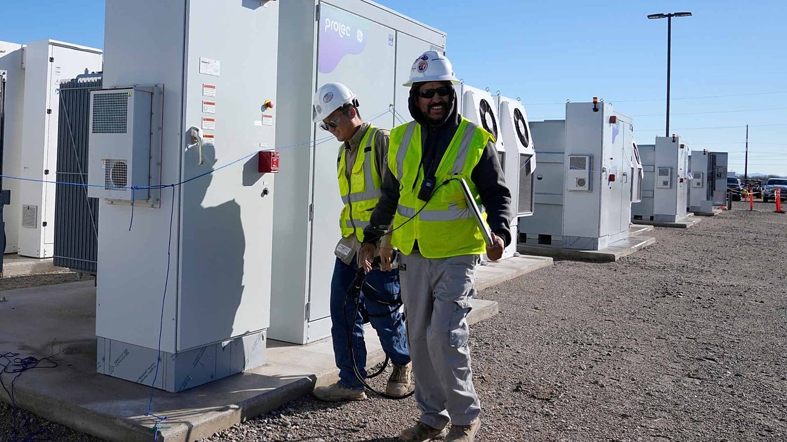Workers walks the campus of battery storage pods at Orsted's Eleven Mile Solar Center lithium-ion battery storage energy facility Thursday, Feb. 29, 2024, in Coolidge, Ariz. 