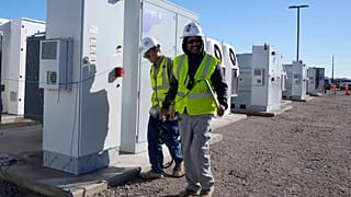 Workers walks the campus of battery storage pods at Orsted's Eleven Mile Solar Center lithium-ion battery storage energy facility Thursday, Feb. 29, 2024, in Coolidge, Ariz.
