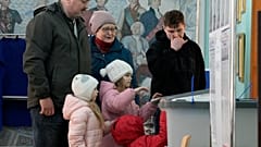 Une famille russe devant une urne électorale, samedi 16 mars 2024.