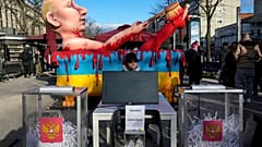 Макет урны для голосования с порванными бюллетенями и моделью президента Путина во время акции протеста возле избирательного участка у посольства России в Берлине