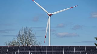Imagen de una turbina eólica detrás de un tejado con módulos solares en Werl, Alemania.