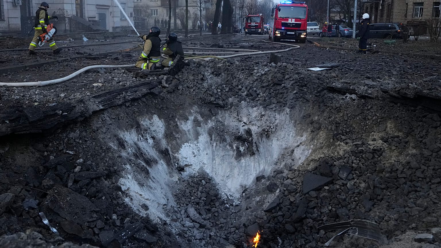 Des pompiers travaillent près du cratère sur le site après une attaque russe à Kyiv, Ukraine, jeudi 21 mars 2024.