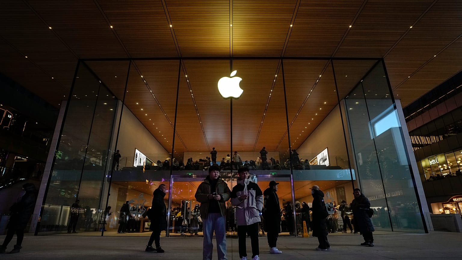 يقف المتسوقون لمشاهدة الناس وهم يزورون متجر Apple Store في مركز تسوق خارجي في بكين