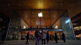 يقف المتسوقون لمشاهدة الناس وهم يزورون متجر Apple Store في مركز تسوق خارجي في بكين
