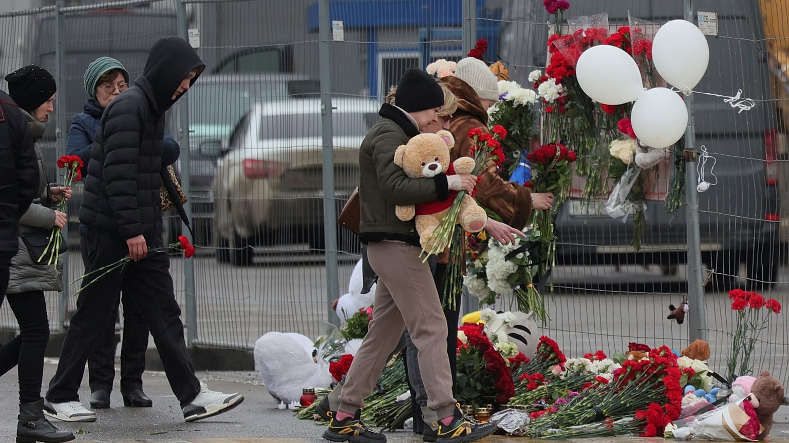 Des personnes déposent des fleurs et des jouets devant le Crocus City Hall, à l'ouest de Moscou, en Russie, le samedi 23 mars 2024.