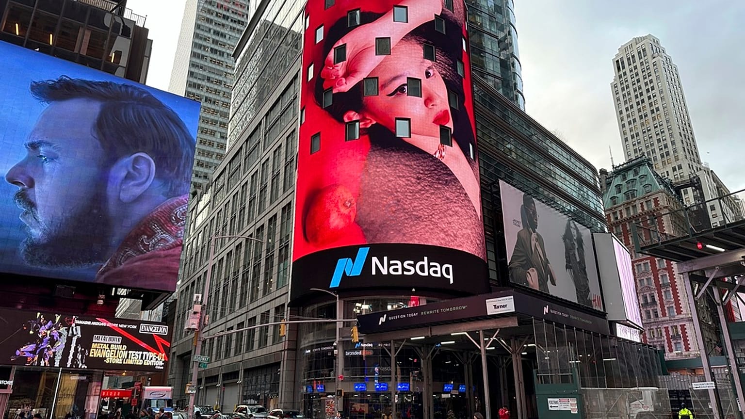 Pedestrians walk past the Nasdaq building in New York on Tuesday, March 26, 2024. 