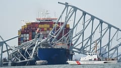 Die Küstenwache fährt an einem Frachter vorbei, das unter einem Teil der Francis-Scott-Key-Brücke festsitzt, nachdem das Schiff am Dienstag, 26. März 2024.