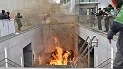 A protestor walks by a fire burning in a stairwell near the metro station during a demonstration outside the European Council building in Brussels, Tuesday 26 March.