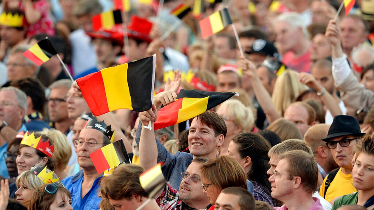 People wave Belgian flags as royal family members arrive outside of the national ball in the Marolles district of Brussels on Saturday, July 20, 2013.