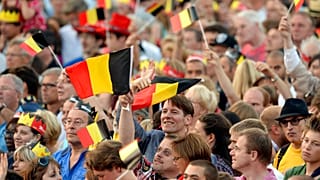 People wave Belgian flags as royal family members arrive outside of the national ball in the Marolles district of Brussels on Saturday, July 20, 2013.