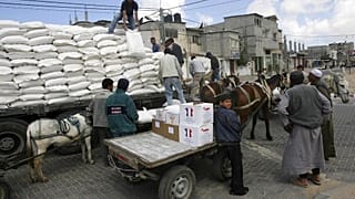 Varios ciudadanos descargan un camión que transporta ayuda humanitaria y alimentos.