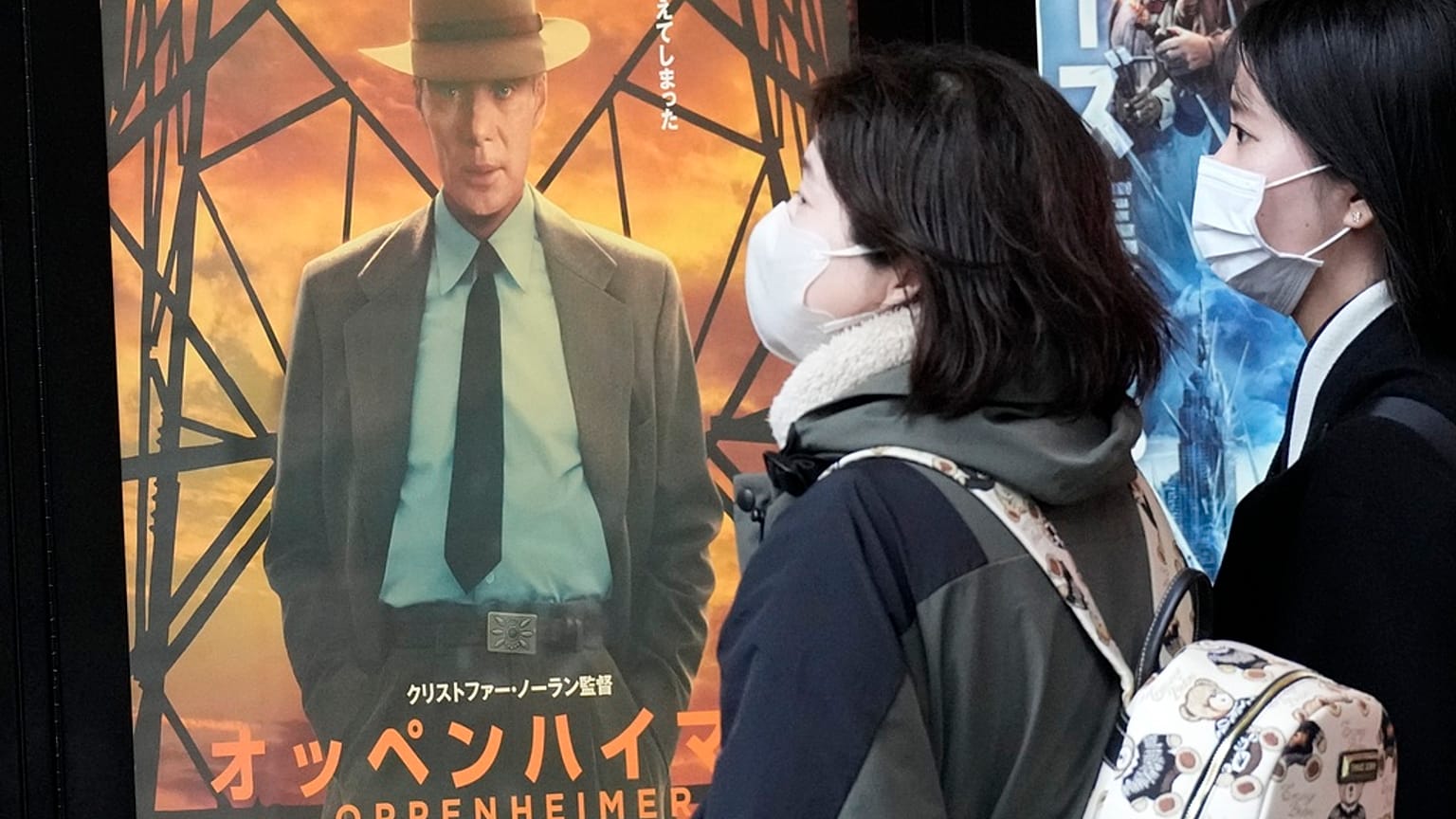 İnsanlar Tokyo'da "Oppenheimer" filmini tanıtan bir posterin yanından geçiyor, 29 Mart 2024 