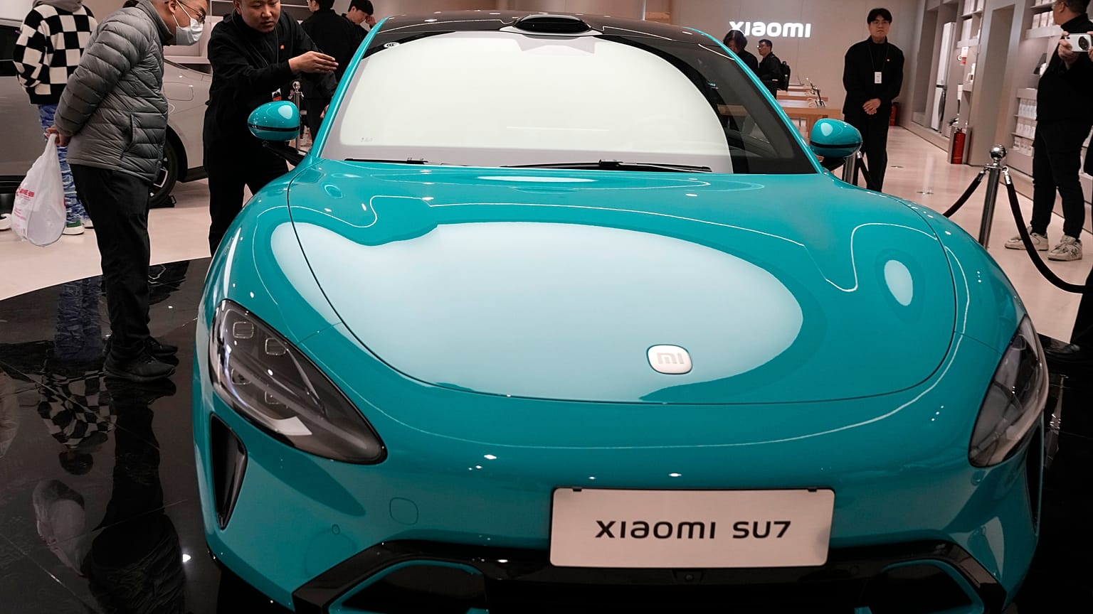 Visitors to the Xiaomi Automobile flagship store look at the Xiaomi SU7 electric car on display in Beijing, Tuesday, March 26, 2024.